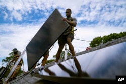 Zaposleni u NY State Solaru, kompaniji za stambene i poslovne fotonaponske sisteme, postavlja solarne panele na krov, New York, august 2022.