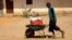 FILE: A person pushes a wheelbarrow with water containers during clashes between the paramilitary Rapid Support Forces and the army in Khartoum North, Sudan, April 22, 2023.