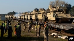 FILE - U.S. soldiers prepare to unload Bradley Infantry Fighting Vehicles from rail cars as they arrive at the Pabrade railway station near Vilnius, Lithuania, Oct. 21, 2019. 