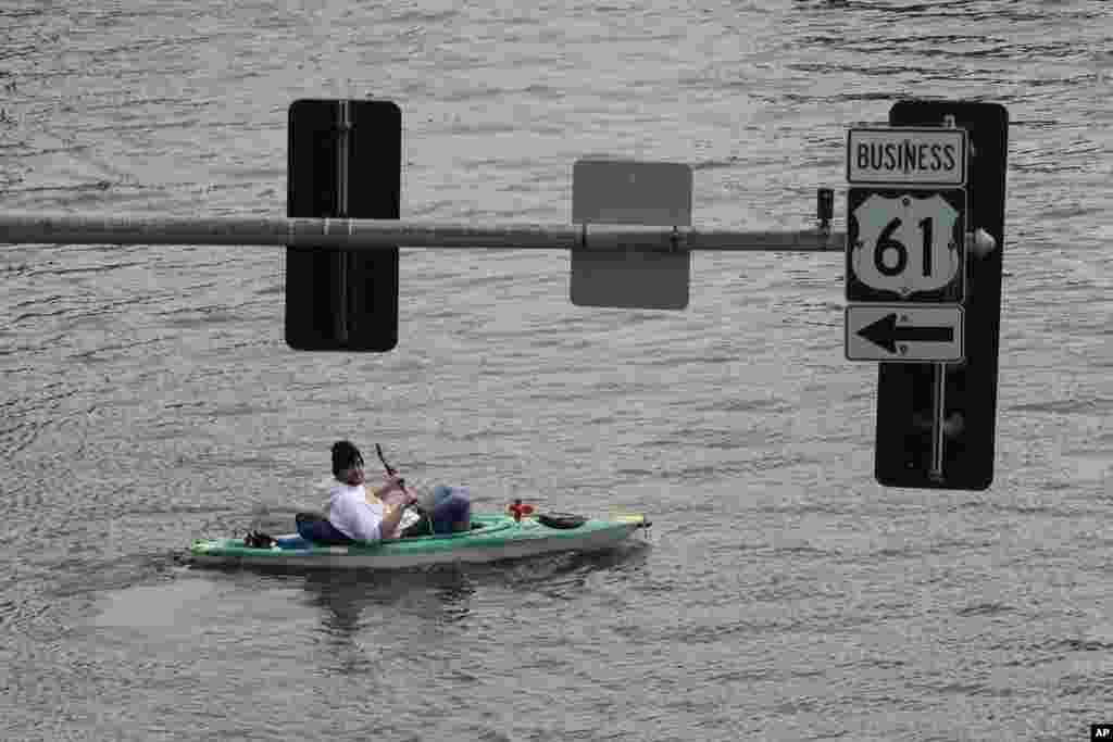 A kayaker floats down a flooded street, May 1, 2023, in downtown Davenport, Iowa. 