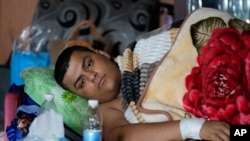 Hussein Maytham lies on a couch in his home in Muqdadiyah, Iraq, March 22, 2023. Hussein was wounded when a car he was in was hit by a planted bomb earlier this month. His parents, two cousins and aunt were killed in the blast.