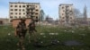 Officers of a special police force walk in front of apartment buildings destroyed by air bombs during the evacuation of local residents from the village of Ocheretine in the Donetsk region on April 15, 2024, amid the Russian invasion in Ukraine.