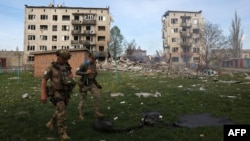 Officers of a special police force walk in front of apartment buildings destroyed by air bombs during the evacuation of local residents from the village of Ocheretine in the Donetsk region on April 15, 2024, amid the Russian invasion in Ukraine.