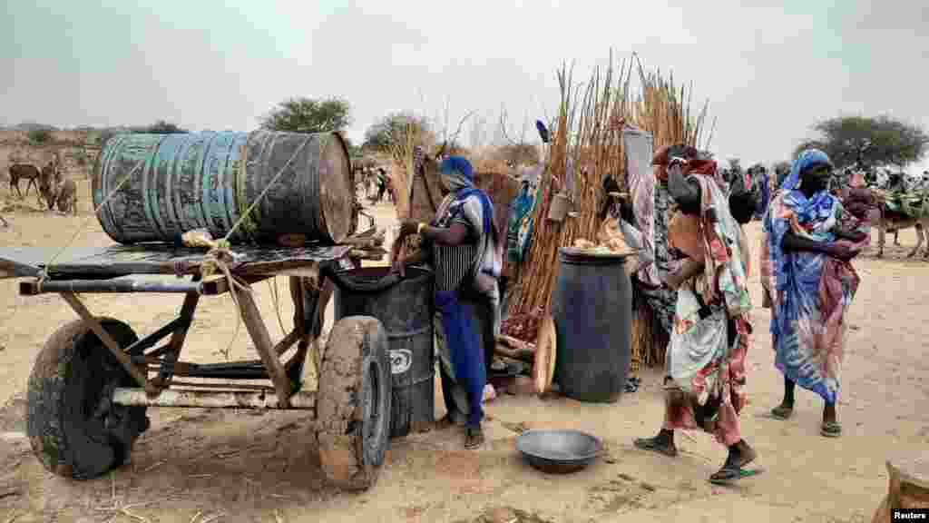 A Sudanese woman who fled the violence in her country tries to get water from a barrel near the border between Sudan and Chad, April 26, 2023. 