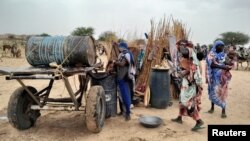 A Sudanese woman who fled the violence in her country tries to get water from a barrel near the border between Sudan and Chad, April 26, 2023. The crisis has sent growing numbers of refugees across Sudan's borders.