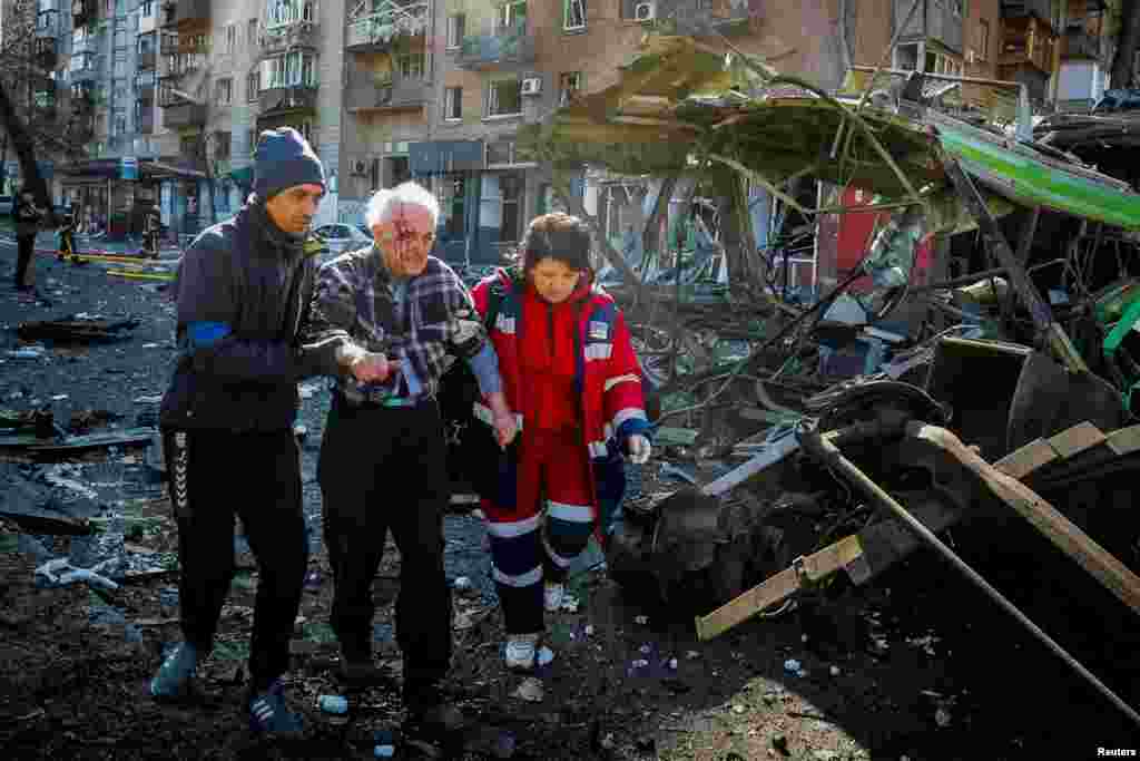 14 de marzo de 2022: Un residente herido durante los bombardeos en Kiev, es ayudado por una sanitaria y un ciudadano, mientras se ve la destrucción en esa parte de la ciudad.