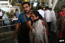 Indian nationals, who were stranded in Sudan, embrace as they exit the domestic terminal of the Chennai International Airport in Chennai, Apr. 27, 2023