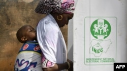 Une mère avec son bébé se prépare à voter dans un bureau de vote à Yola, dans l'État d'Adamawa, le 25 février 2023, lors des élections présidentielles et générales au Nigeria.