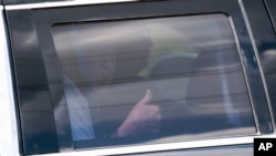 Former U.S. President Donald Trump gives a thumbs-up as he sits in the rear of his limousine departing Trump International Golf Club in West Palm Beach, Florida, April 2, 2023.
