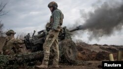 Ukrainian service members fire a howitzer M119 at a front line, near the city of Bakhmut, March 10, 2023.