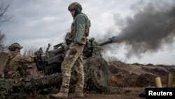 Ukrainian service members fire a howitzer M119 at a front line, near the city of Bakhmut, March 10, 2023.