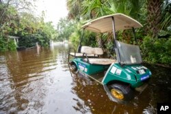 A golf cart sits in floodwater on Atlantic Avenue in Sullivan's Island, South Carolina, as Tropical Storm Debby approaches, Aug. 7, 2024.