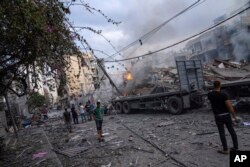 Palestinians walk amid the rubble following Israeli airstrikes that razed swaths of a neighborhood in Gaza City, Oct. 10, 2023.