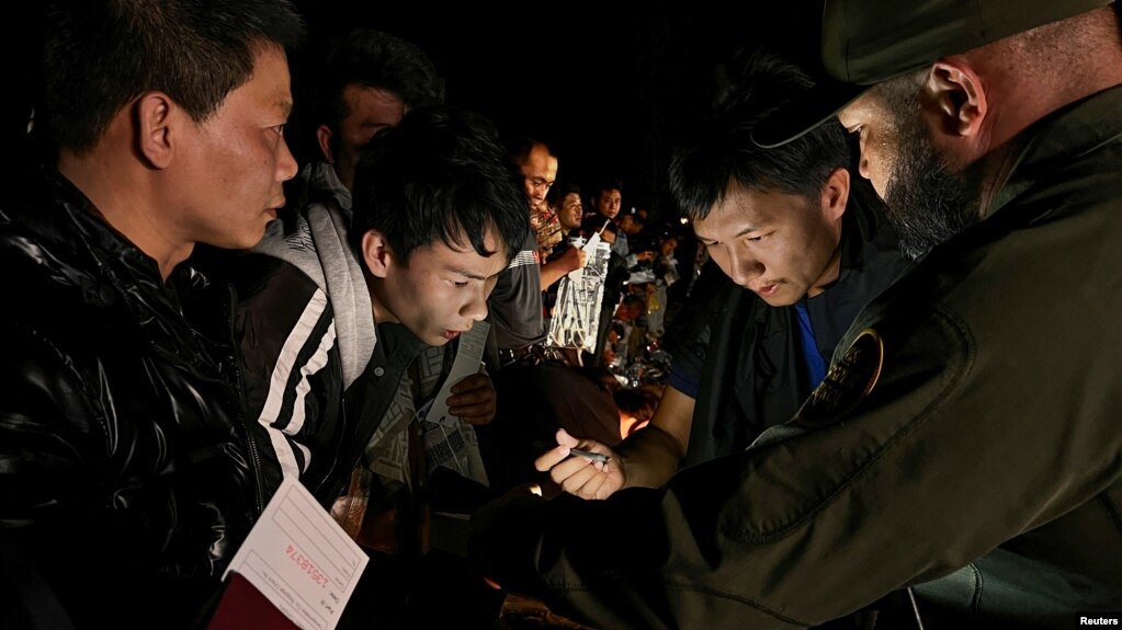 一名中国人正在给一群渡过美墨边境的格兰德河进入美国德克萨斯州的中国人当翻译，向美国边境巡逻人员报到登记，以便进入移民程序。（资料照片：2023年3月23日）(photo:VOA)