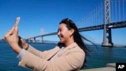 Content creator Cynthia Huang Wang works below the San Francisco-Oakland Bay Bridge in San Francisco, April 8, 2024. 