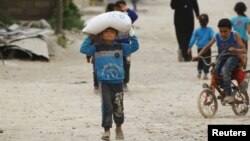 FILE - A boy carries food aid given by UN's World Food Program in Raqqa, Syria, April 26, 2018.
