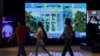 People walk by a TV screen showing CCTV broadcasting news that U.S. President Joe Biden dropped out the presidential race, at a shopping mall in Beijing, July 22, 2024. 