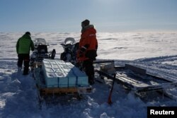 Norwegian Polar Institute glaciologist Jean-Charles Gallet (R) and Italian National Research Council glaciologist Federico Scoto pull sleds loaded with boxes of ice cores for Ice Memory from the Holtedahlfonna icefield waiting to be brought back for storage to Ny-Aalesund, April 10, 2023.