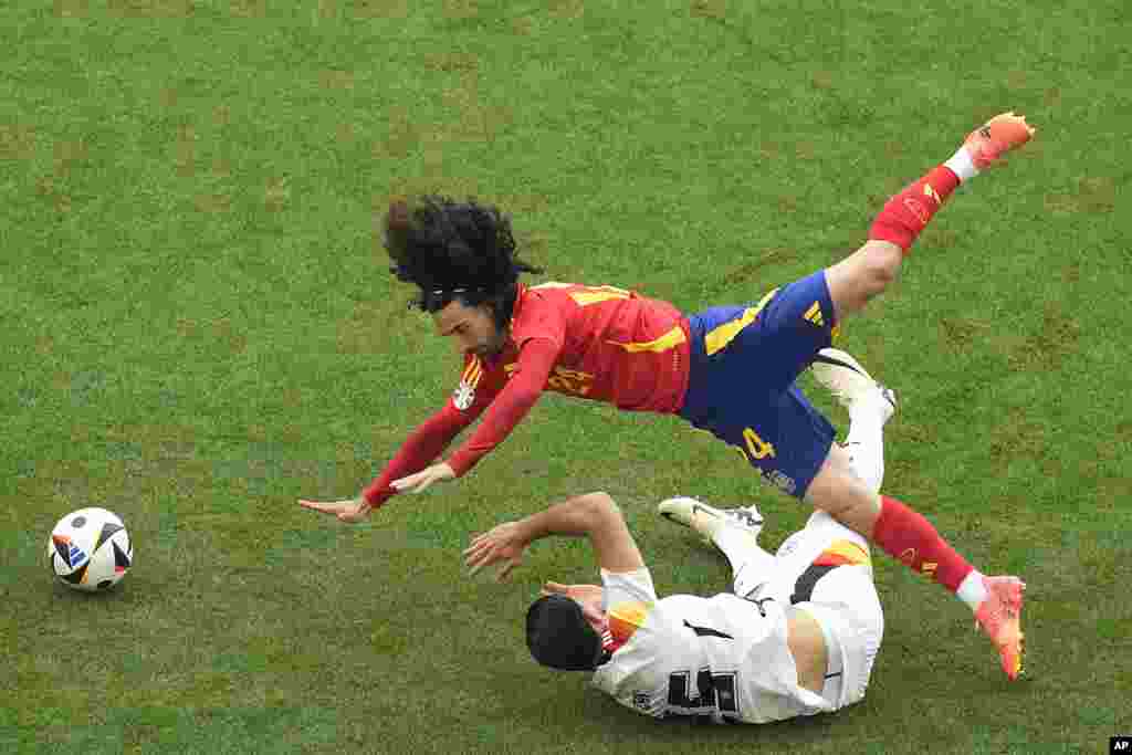 Spain's Marc Cucurella, top, falls over Germany's Emre Can during a quarter final match between Germany and Spain at the Euro 2024 soccer tournament in Stuttgart, Germany.