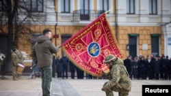 Ukrajinski predsjednik Volodimir Zelenski predaje zastavu vojniku tokom ceremonije posvećene prvoj godišnjici ruske invazije na Ukrajinu, Kijev, 24. februar 2023.