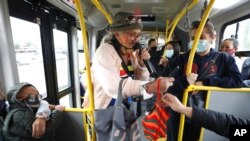 Marlene Alfonso, una abuela venezolana de 69 años que se hace llamar “Toothless Cindy”, acepta monedas de los viajeros mientras canta sobre la vida de los inmigrantes venezolanos en un autobus en Bogotá, Colombia, el martes 3 de noviembre de 2020.