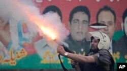 A riot police officer fires tear gas to disperse supporters of former Prime Minister Imran Khan during clashes outside Khan's residence, in Lahore, Pakistan, March 14, 2023. 