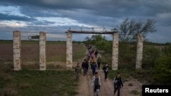 美國德州國民警衛隊成員帶領一群來自中國和中美洲的移民走過德州的農地。（2023年4月10日）