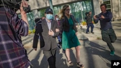 "Harry" Lu Jianwang, second from left, leaves Brooklyn federal court with his lawyer after his arraignment, April 17, 2023, in New York. Justice Dept. officials say Jianwang was arrested on charges that he helped establish a secret police outpost on behalf of the Chinese govt.