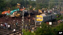 Onlookers are seen gathered as crews work at the site of a deadly train derailment in Balasore district, in the eastern Indian state of Odisha, June 4, 2023.