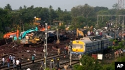 Sejumlah warga tampak berkumpul di lokasi kecelakaan kereta di distrik Balasore, Orissa, di timur India pada 4 Juni 2023. (Foto: AP/Rafiq Maqbool)