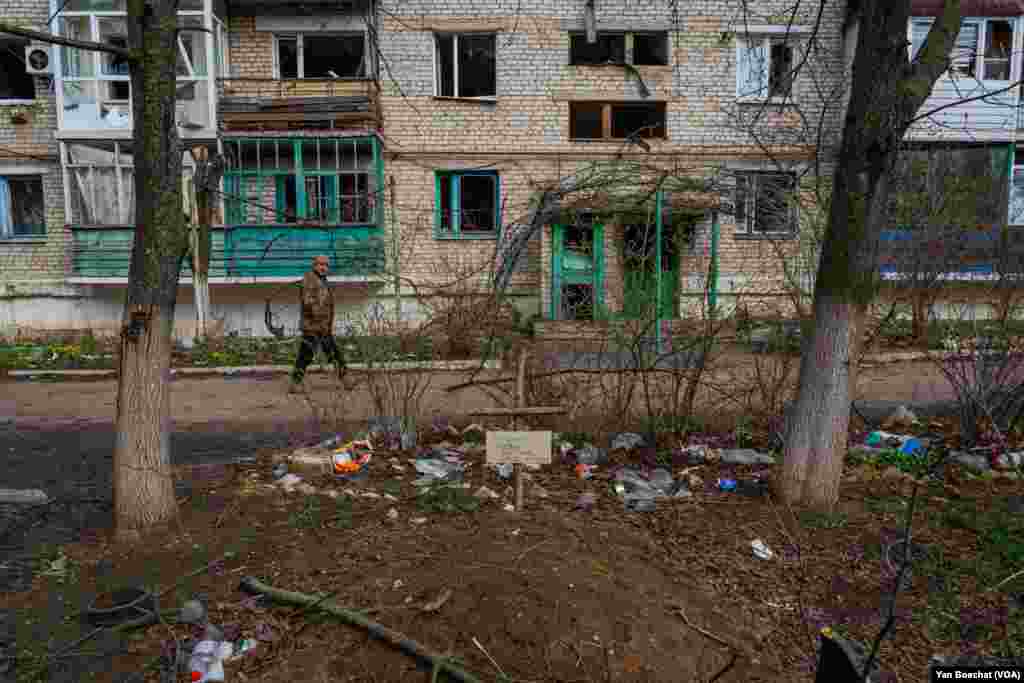A local resident passes by a grave inside the common area of a complex of residential buildings in Siversk, April 4, 2023.