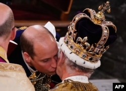 Britain's Prince William, Prince of Wales kisses his father, Britain's King Charles III, wearing St. Edward's Crown, during the King's Coronation Ceremony inside Westminster Abbey in London, May 6, 2023.