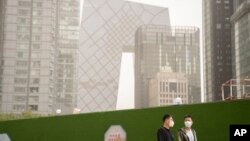 資料照：北京市民帶著口罩走過北京中心商務區。（2023年4月25日）