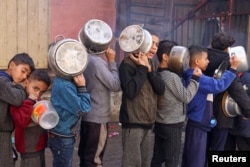 Anak-anak Palestina mengantre untuk mendapatkan makanan yang dimasak dapur amal, di tengah kekurangan pasokan makanan di Rafah di Jalur Gaza selatan, 14 Desember 2023. (Foto: Saleh Salem/REUTERS)