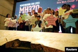 Anggota keluarga korban berfoto bersama dengan puing-puing pesawat Malaysia Airlines MH370 yang hilang selama acara peringatan tahunan keenam di Putrajaya, Malaysia, 7 Maret 2020. (Foto: Reuters)