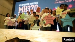 FILE - Family members of the victims pose for a group picture with a debris of the missing Malaysia Airlines flight MH370 during its sixth annual remembrance event in Putrajaya, Malaysia, March 7, 2020.