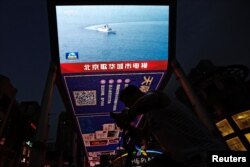A screen broadcasts news footage of a Navy Force vessel taking part in military drills by the Eastern Theatre Command of China's People's Liberation Army around Taiwan, in a shopping area in Beijing, China, Aug. 19, 2023.