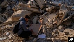 A man writes a note with contact details in case a body is retrieved under the rubble of a destroyed building in Antakya, southeastern Turkey, Feb. 13, 2023. 