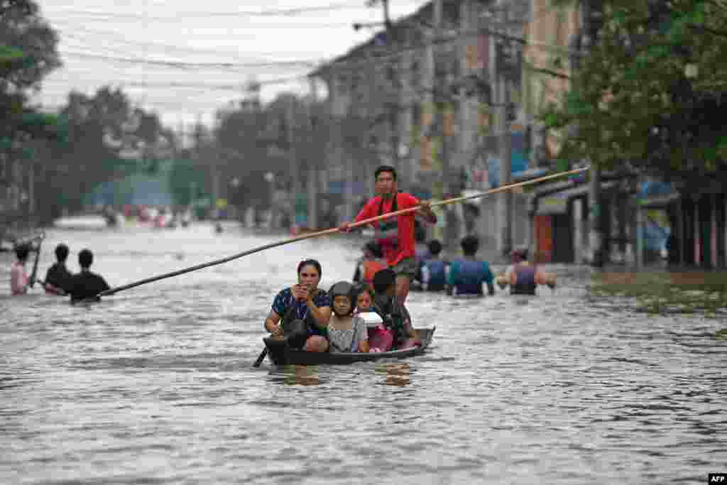 Локалните жители се пробиваат низ поплавената улица по обилните дождови во регионот Баго во Мјанмар.