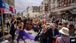Musicians play their instruments as people sit at long tables to eat their lunch as part of the Big Lunch celebration in London.&nbsp;The Big Lunch is part of the weekend of celebrations for the Coronation of King Charles III.