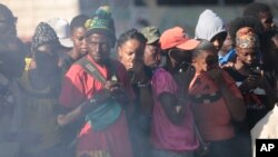 FILE - Bystanders look at the bodies of alleged gang members that were set on fire by a mob after they were stopped by police while traveling in a vehicle in Port-au-Prince, Haiti, April 24, 2023.