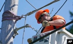 FILE - Travis Sheetz, a worker with the Mason County (Wash.) Public Utility District, installs fiber optic cable on a utility pole, Aug. 4, 2021, near Belfair, Washington.