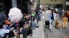 FILE - Migrants sit in a queue outside of the Roosevelt Hotel, which is being used by the city as temporary housing for migrants bused to New York from Texas, July 31.