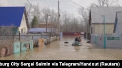People row a boat in a flooded street in Orenburg, Russia, in this still image taken from video released, April 8, 2024. 