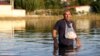 A man walks into floodwaters to deliver medicines to a relative after the country's rainstorm record, in the town of Palamas, near Karditsa, Thessaly region, central Greece, Sept. 8, 2023. 