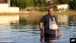 A man walks into floodwaters to deliver medicines to a relative after the country's rainstorm record, in the town of Palamas, near Karditsa, Thessaly region, central Greece, Sept. 8, 2023. 