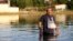 A man walks into floodwaters to deliver medicines to a relative after the country's rainstorm record, in the town of Palamas, near Karditsa, Thessaly region, central Greece, Sept. 8, 2023. 