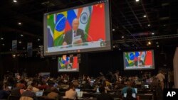 Members of the media watch Russia's President Vladimir Putin address, via videolink, the 2023 BRICS Summit in Johannesburg, South Africa, Aug. 23, 2023.