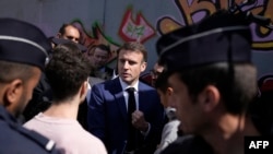 French President Emmanuel Macron, center, meets with residents during a visit focusing on security and the fight against drug trafficking, in La Castellane district of Marseille, southeastern France, on March 19, 2024. 