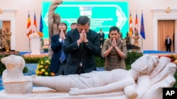 In this photo released by Agence Kampuchea Press (AKP), Cambodian Prime Minister Hun Manet prays with others during a ceremony for the return of artifacts in Peace Palace in Phnom Penh, Cambodia, Thursday, Aug. 22, 2024. (AKP via AP)